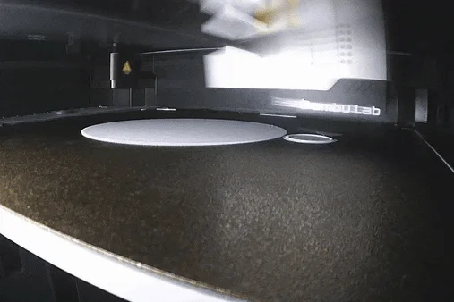 A 3D printer building a part on its print bed.