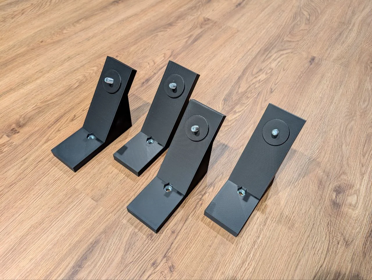 Four black printed wedges with metal fasteners, arranged on a wooden surface.